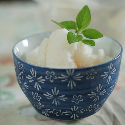 Coconut lychee sorbet garnished with a sprig of mint
