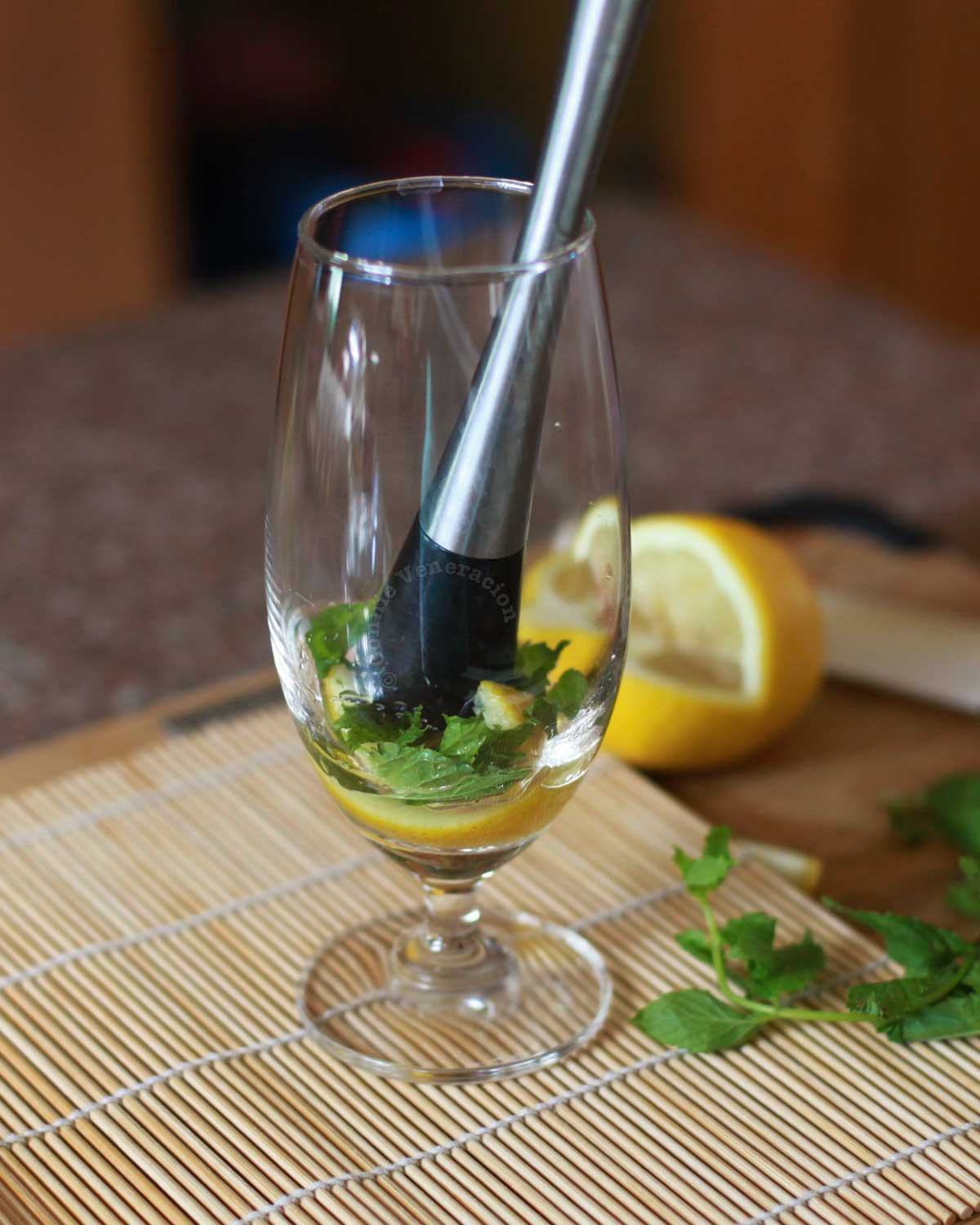 Muddling lemon and mint in a glass