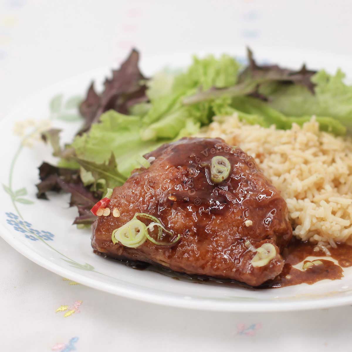 Filipino sweet sour roast chicken stew (paksiw na lechon manok) on plate with rice and side salad