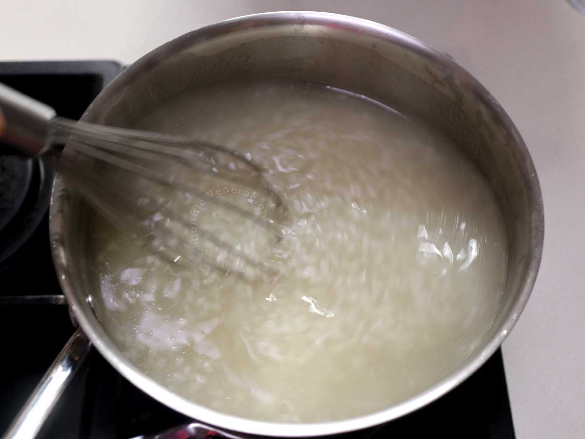 Using a wire whisk to break up rice grains when cooking congee