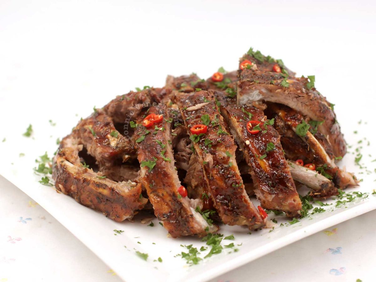 Cajun Pork Spare Ribs on Serving Plate Garnished with Sliced Chilies and Chopped Parsley
