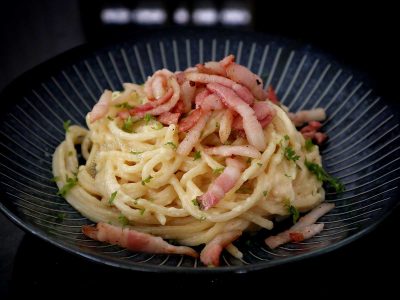 Pasta Alfredo topped with bacon and parsley