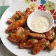 Baked Buffalo chicken wings with dipping sauce on serving plate