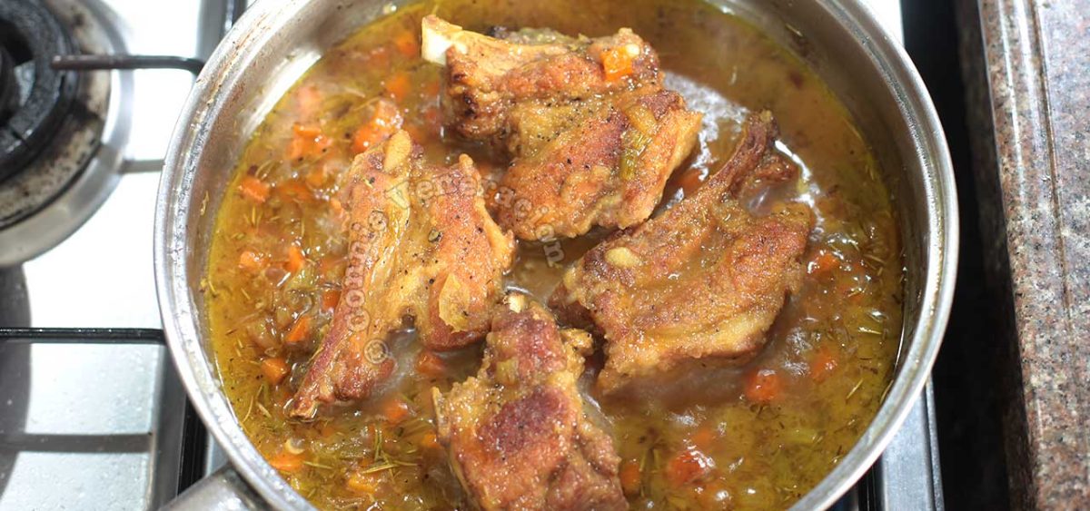 Browned pork ribs in pan with beer and vegetables