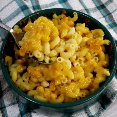Scooping baked mac and cheese from baking bowl