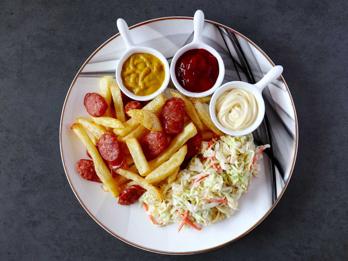 Salchipapas with mustard, ketchup and mayo, and coleslaw on the side