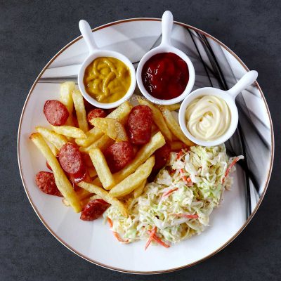 Salchipapas with mustard, ketchup and mayo, and coleslaw on the side
