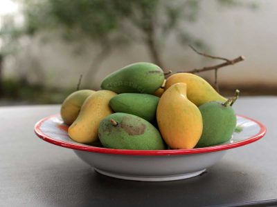 A bowl of green and ripe mangoes