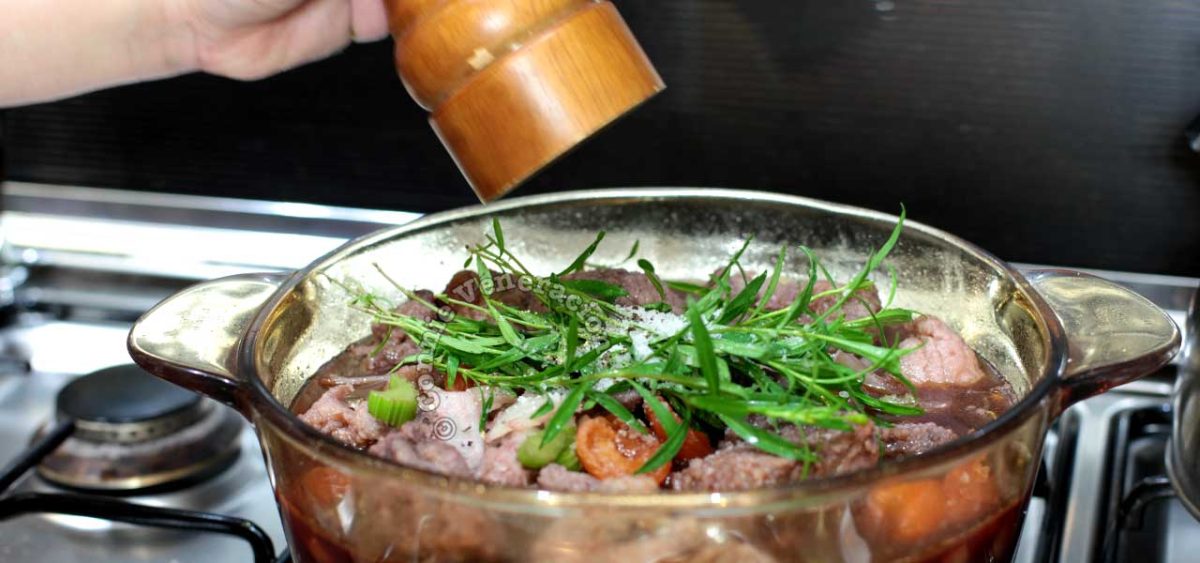 Sprigs of tarragon on top of beef and apricots in pot