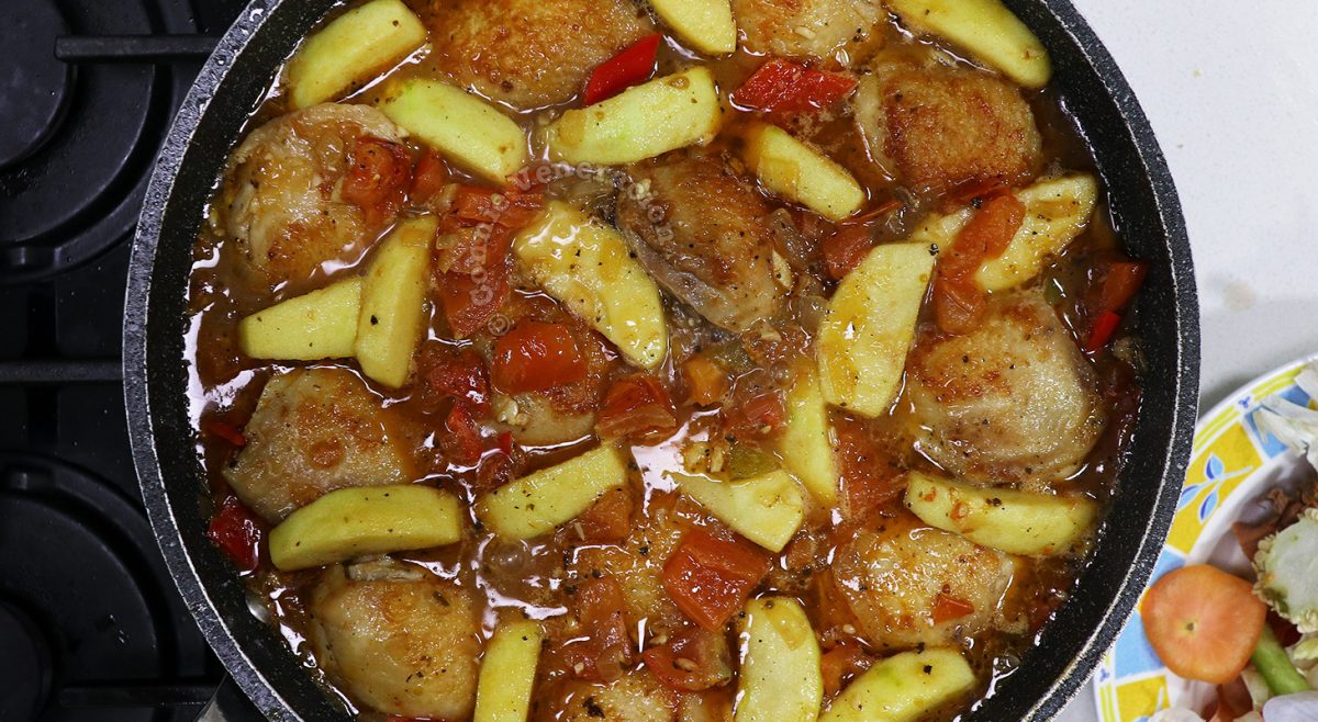 Stewing chicken, vegetables and apples in pan