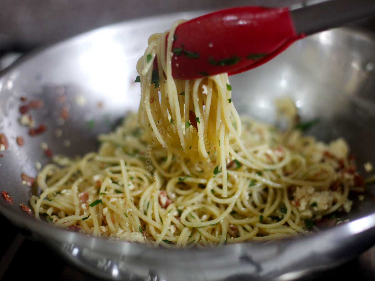 Lifting cooked pasta from the pan using kitchen tongs