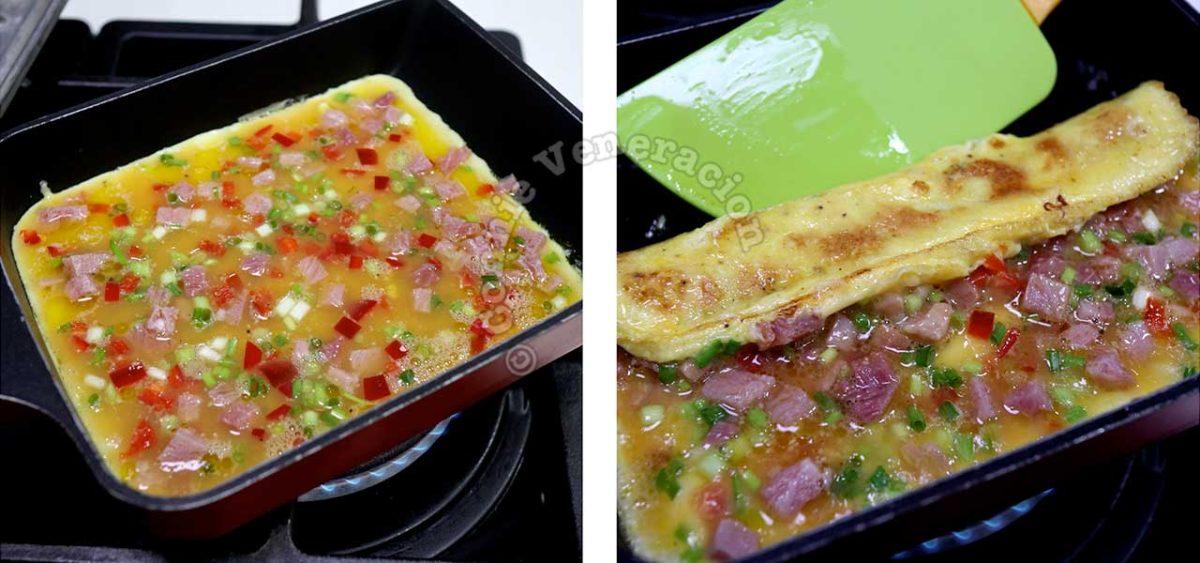 Eggs in pan sprinkled with finely sliced scallions, chopped bell pepper and ham