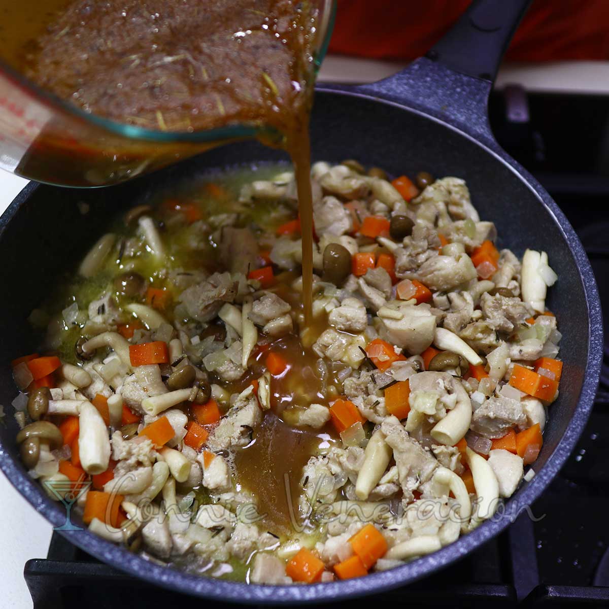 Pouring gravy over chicken, mushrooms and vegetables in pan