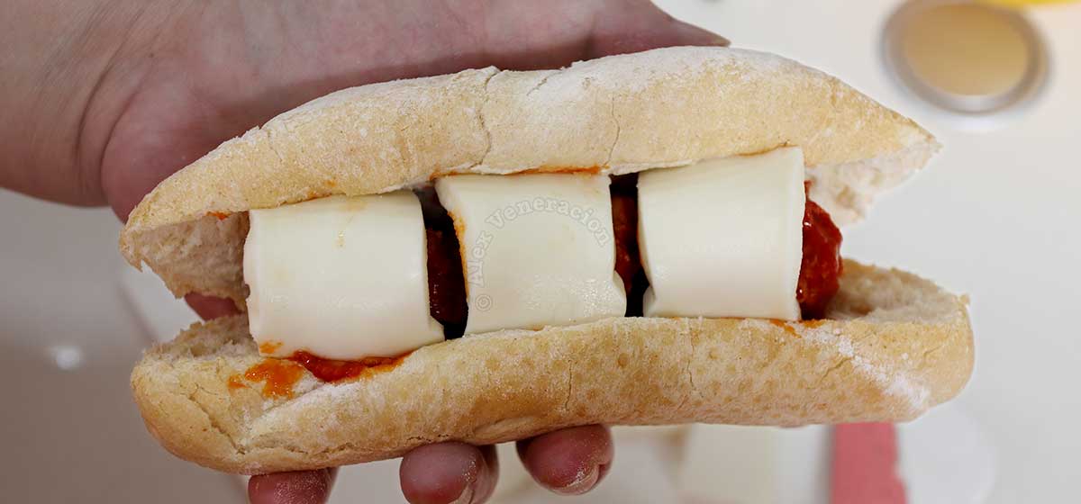 Topping meatball filling of a baguette with mozzarella slices