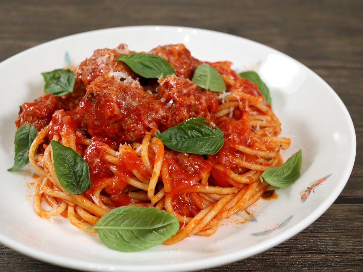 Spaghetti and meatballs garnished with grated Pecorino and basil leaves