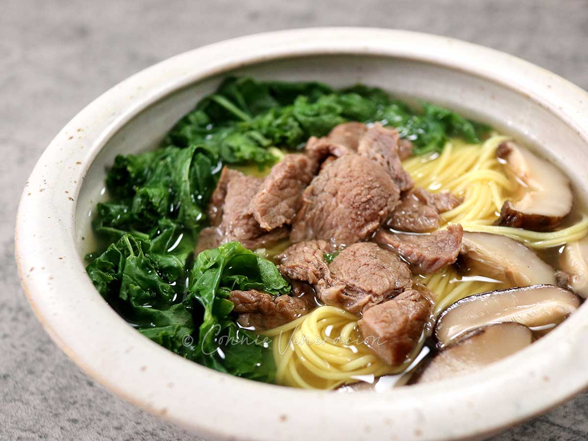 Beef, shiitake and kale noodle soup in stoneware bowl