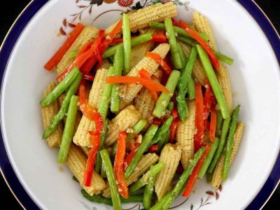 A side dish of baby corn and asparagus in serving bowl
