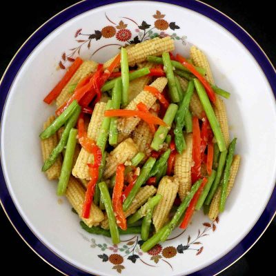A side dish of baby corn and asparagus in serving bowl