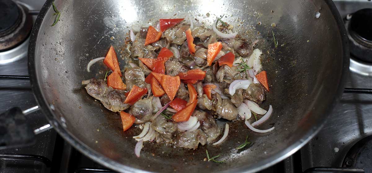 Stir frying chicken gizzards with spices and vegetables in wok