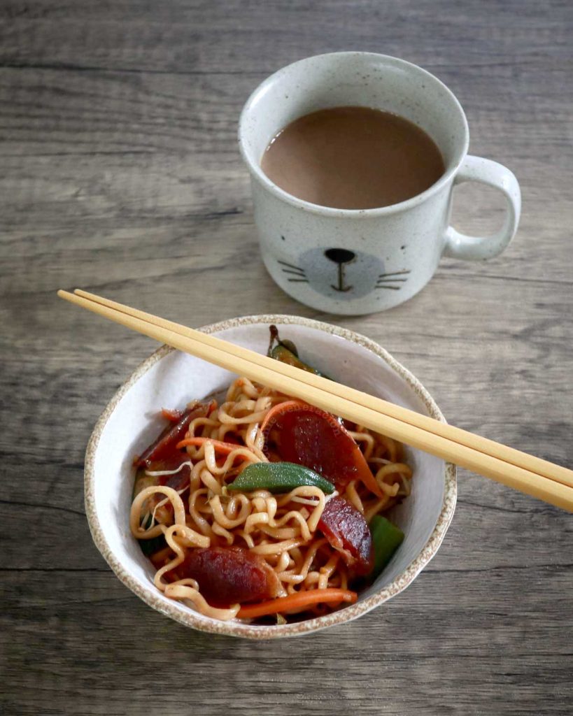 Stir fried noodles in bowl with coffee in background