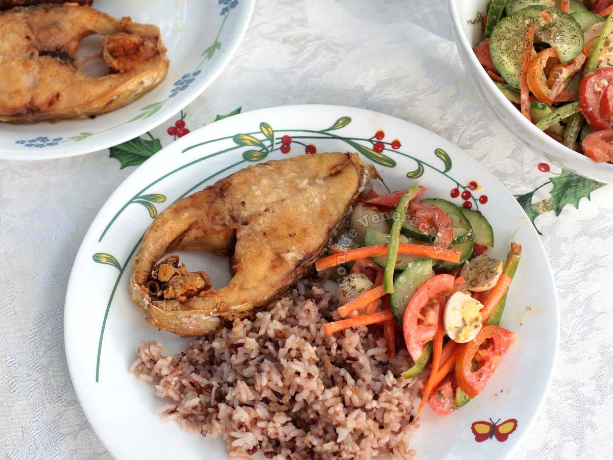 Salted quail eggs and vegetable salad, fried fish steak and brown rice on plate