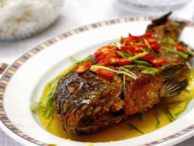 Fried whole tilapia with sweetened calamansi sauce garnished with chili slices and scallions
