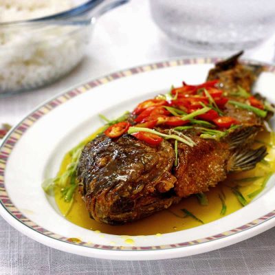 Fried whole tilapia with sweetened calamansi sauce garnished with chili slices and scallions