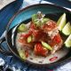 Crispy pork belly in coconut cream sauce garnished with slices of red and green chilies and served with kaffir lime wedges on the side