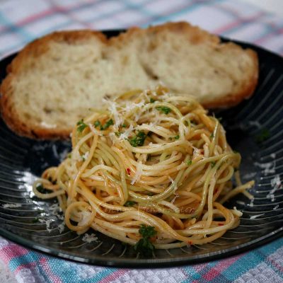 Spaghettini aglio e olio with bread in shallow bowl