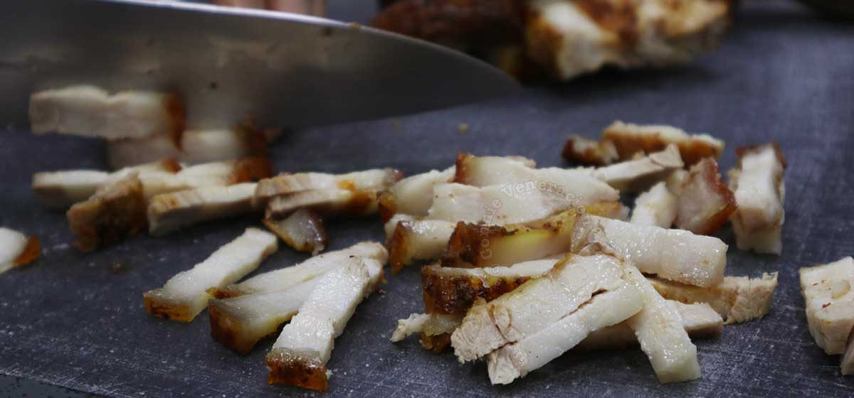 Cutting crispy pork belly into thin strips