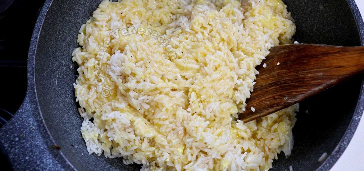 Stirring beaten eggs with rice in wok