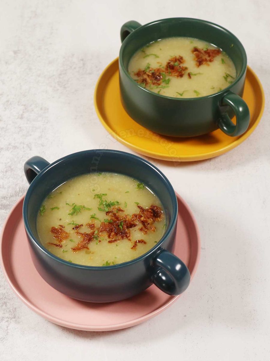 Two bowls of Pureed leeks and potato soup garnished with fried shallots