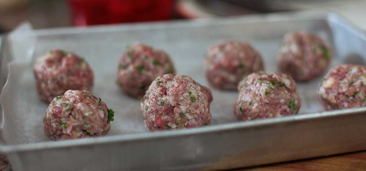 Uncooked meatballs in baking pan