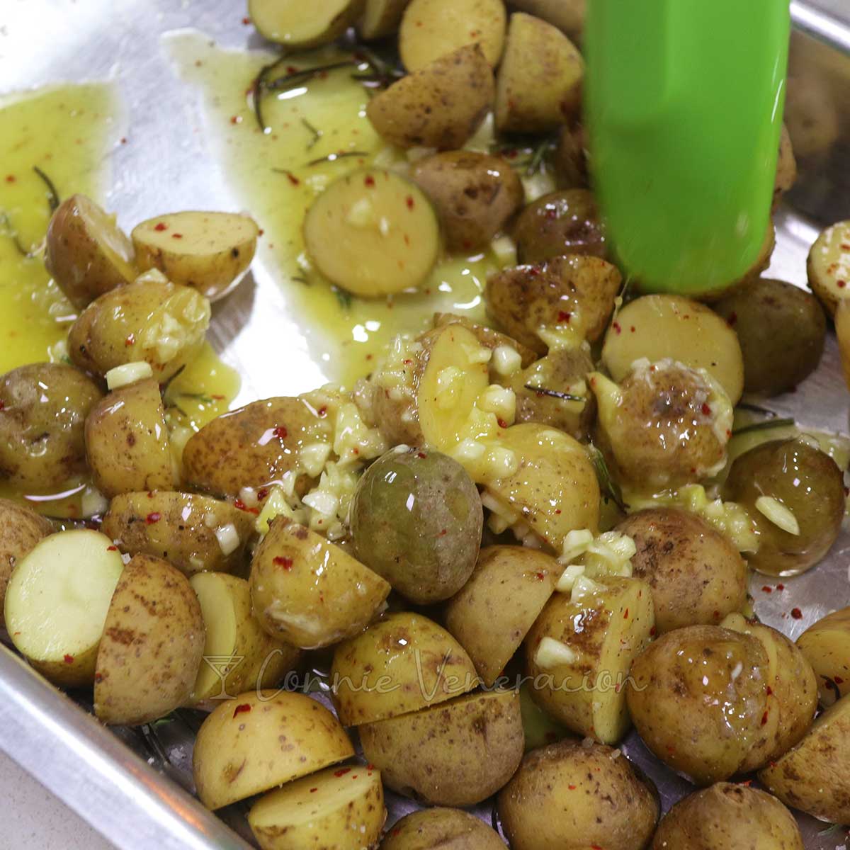 Stirring baby potatoes in baking tray