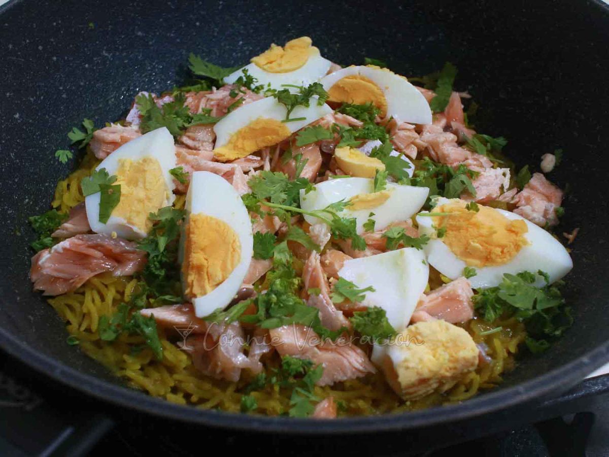 Adding salted salmon, egg quarters, cilantro and parsley to cooked curry rice in pan