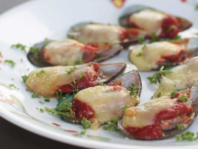 Mussels on the half shell topped with tomato sauce and cheese