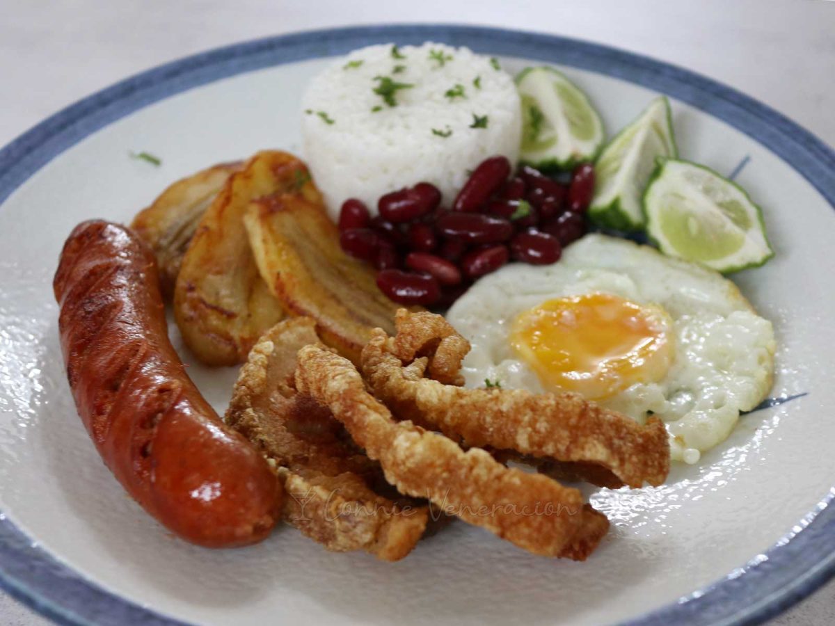 Home version of Colombian bandeja paisa with chorizo, chicharron, fried egg and bananas are served with rice and beans