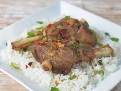 Thai-inspired braised lamb shanks garnished with chilies and mint leaves