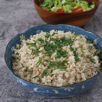 Rice in bowl with salad in the background