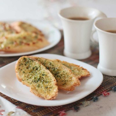 Garlic and herb toast on plate with coffee on the side