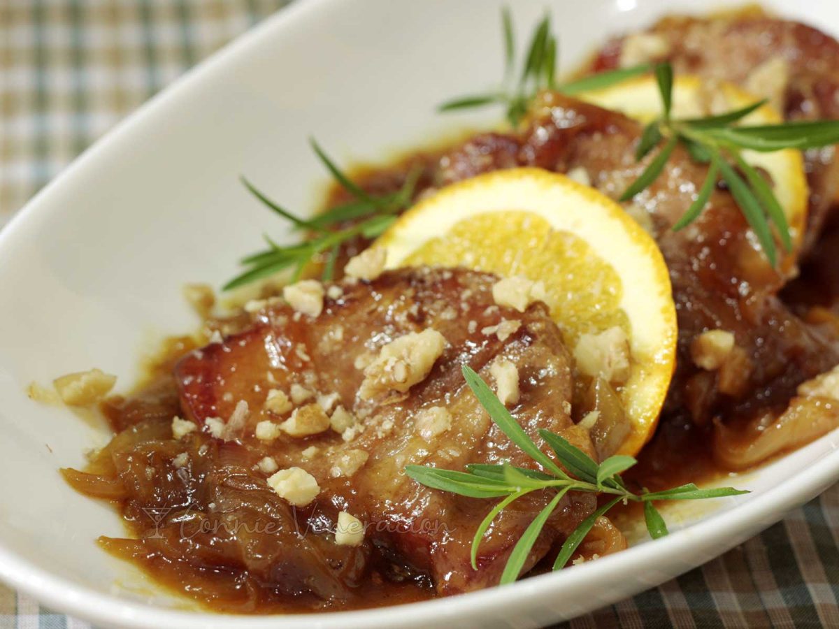 Pork chops with honey orange sauce garnished with tarragon and nuts