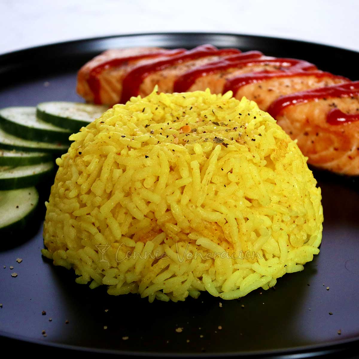 Indonesian yellow rice (nasi kuning) with fish and cucumbers on the side