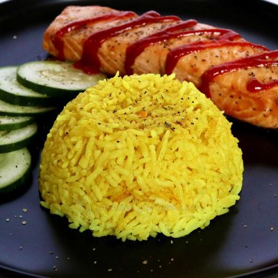Indonesian yellow rice (nasi kuning) with fish and cucumbers on the side