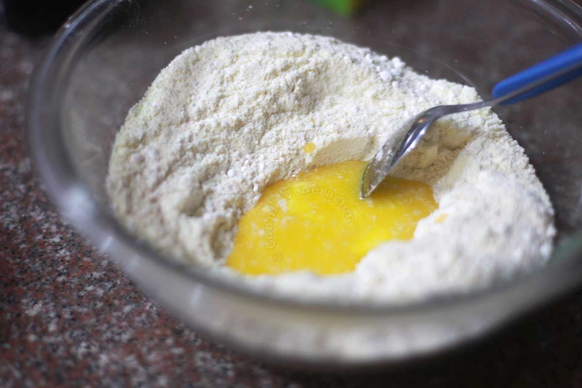 Adding melted butter to toasted flour, sugar and powdered milk to make polvoron