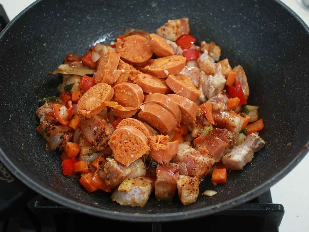 Sliced chorizo over pork in pan