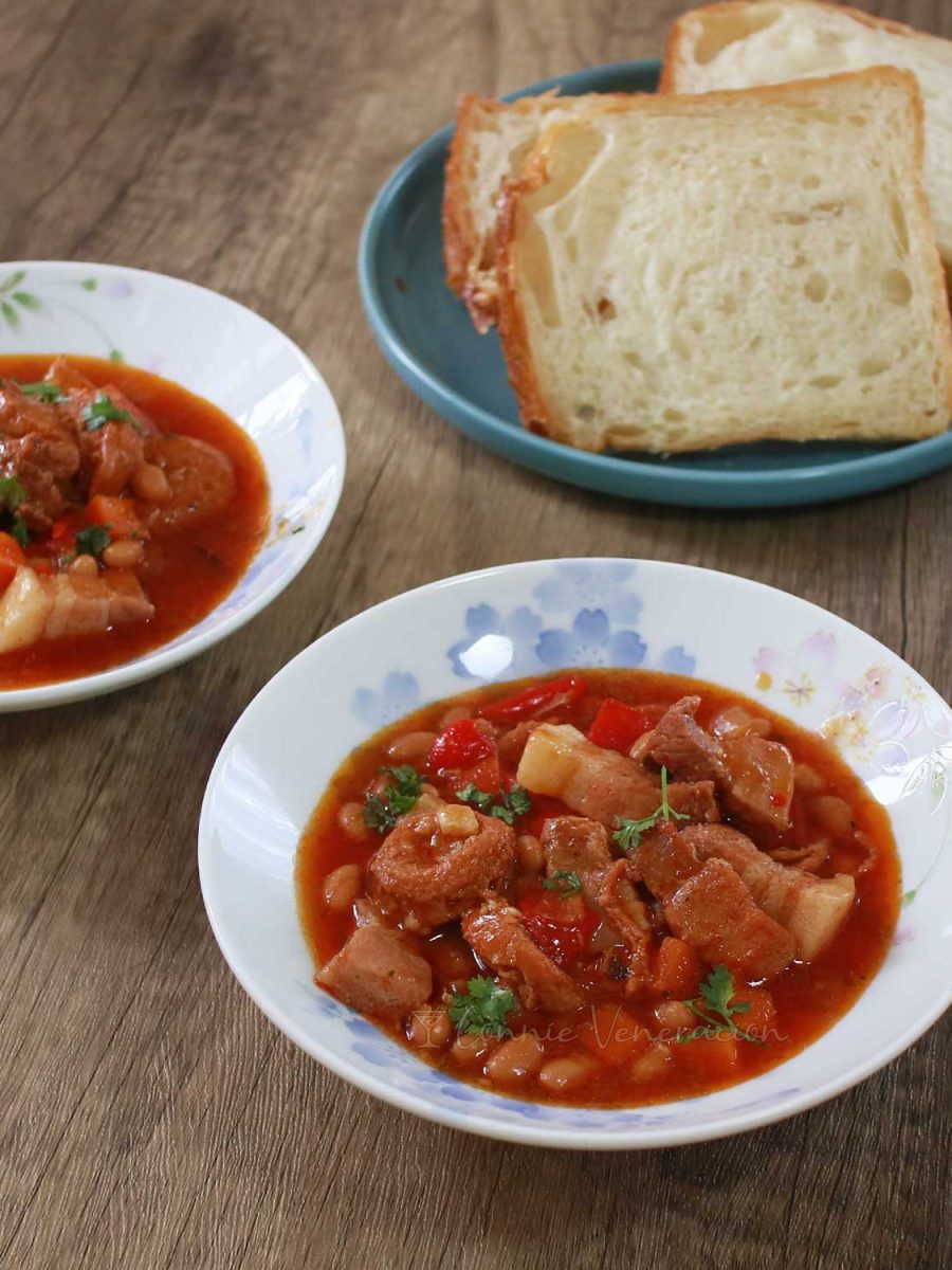 Pork, sausage and beans in bowls with bread on the side