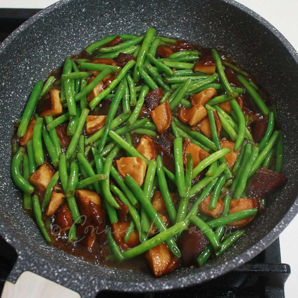 Shiitake and green bean stir fry with teriyaki sauce in cooking pan