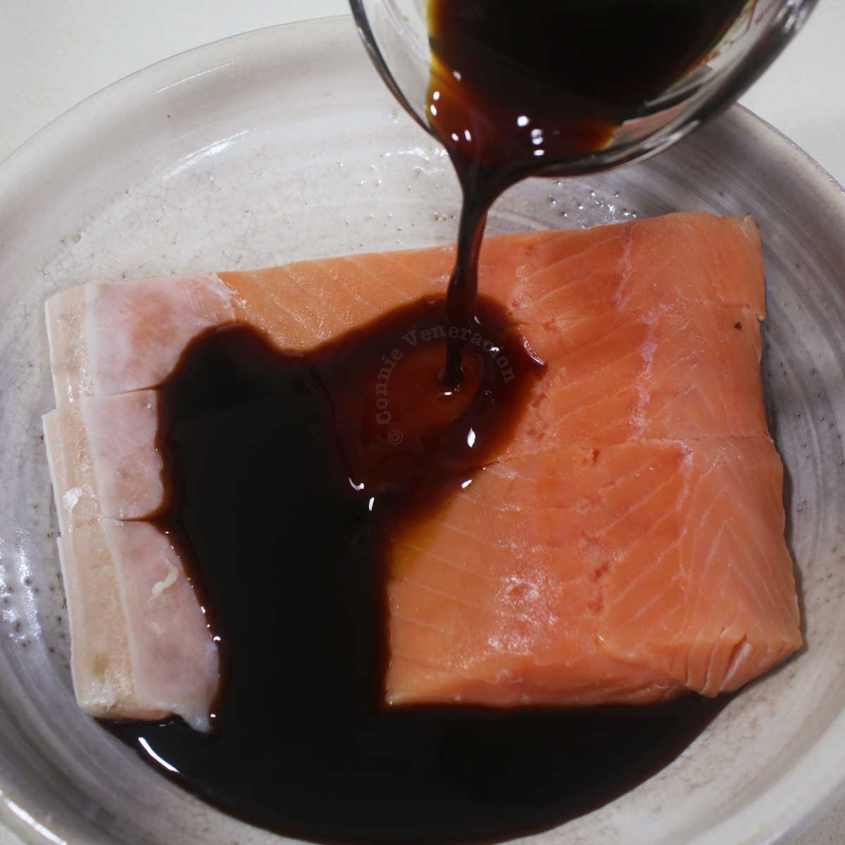 Pouring reduced teriyaki sauce over salmon fillets