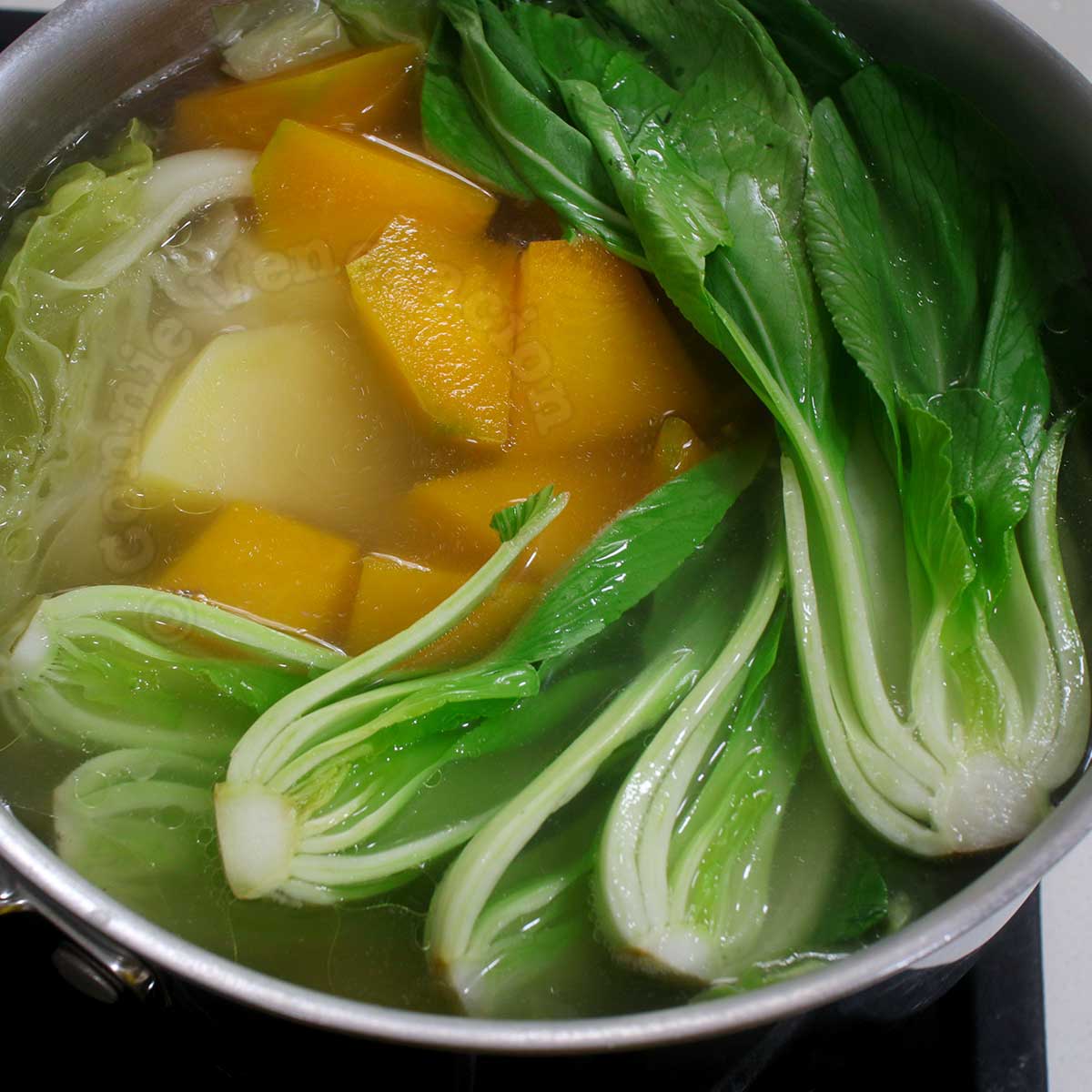Boiling squash, potattoes, cabbage and bok choy in chicken broth