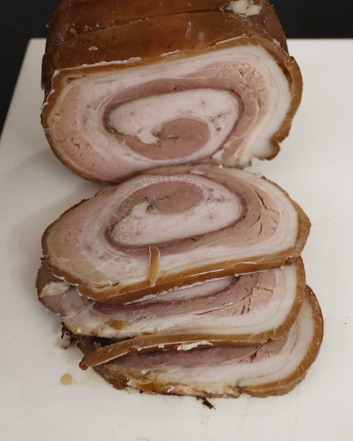 Sliced chashu (Japanese rolled and braised pork belly) on white chopping board